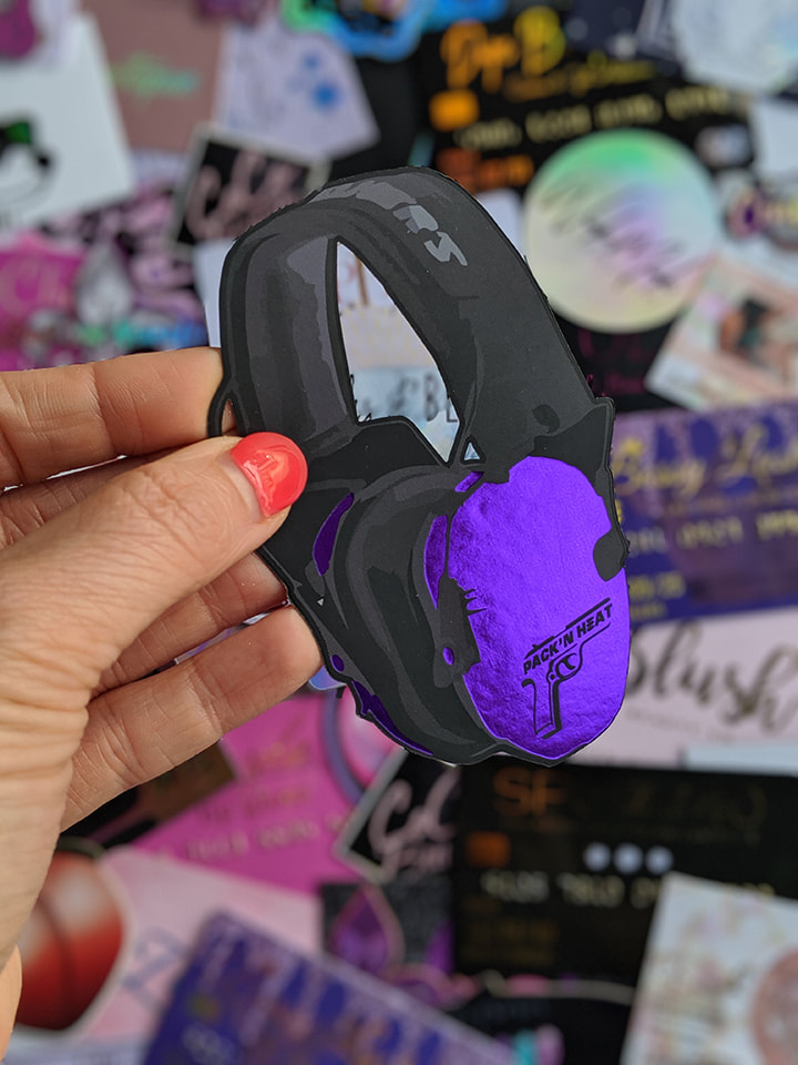 Purple foil business cards in the shape of earmuffs. Pack 'n Heat makes custom crystal hearing protection for ladies who shoot guns. Our die cut business cards were the PERFECT solution for building brand awareness. She even has touches of holographic foil on the backside.
